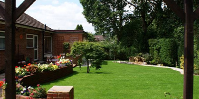 person mowing the lawn in a garden with vibrant flowers showcasing a neat grassy area promoting healthy garden maintenance and outdoor care 4 lawn care tips