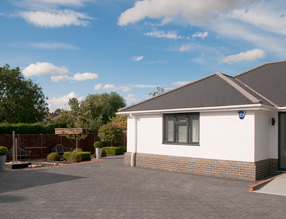 modern house exterior with driveway surrounded by greenery and garden features including trees and stone paths perfect for three car parking